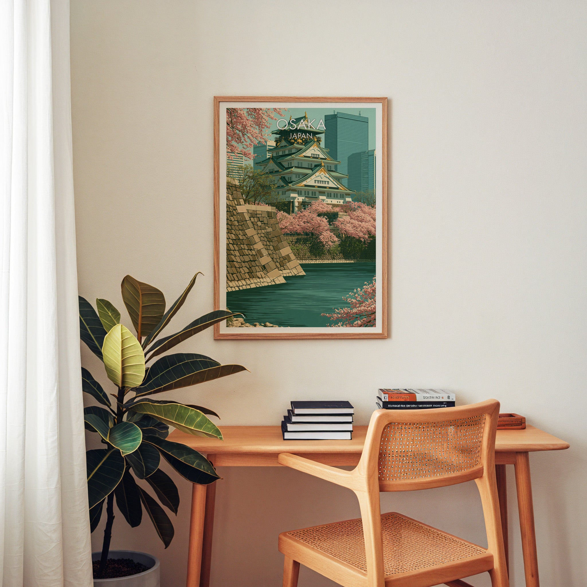 Osaka Castle Japan wall art above a wooden home office desk with a rattan chair and books