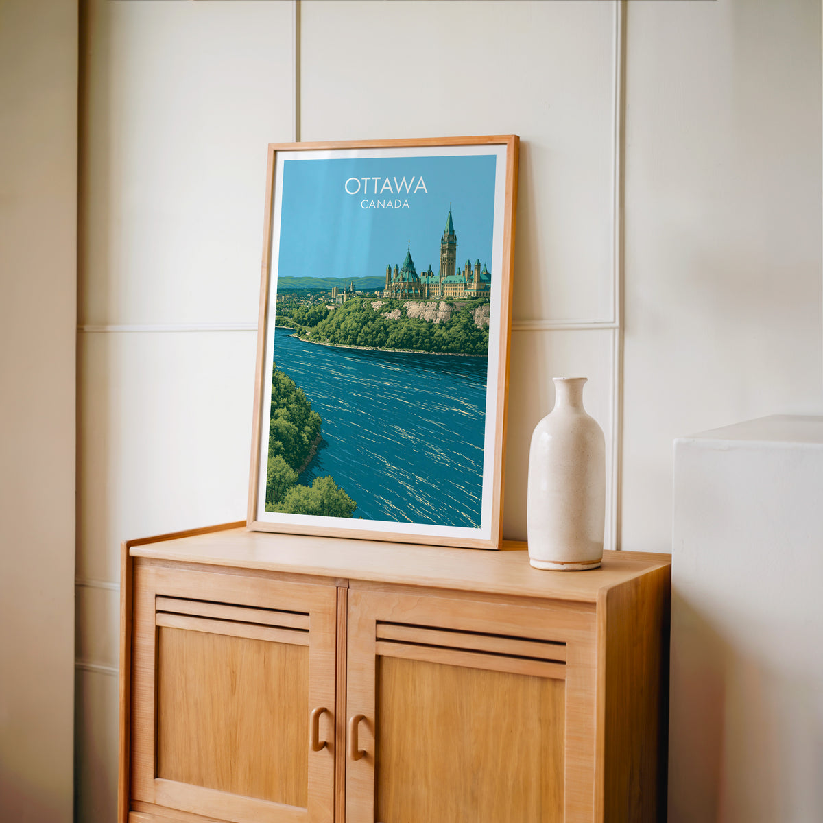 Ottawa Peace Tower wall art in an oak frame on a light wood cabinet beside a stoneware vase