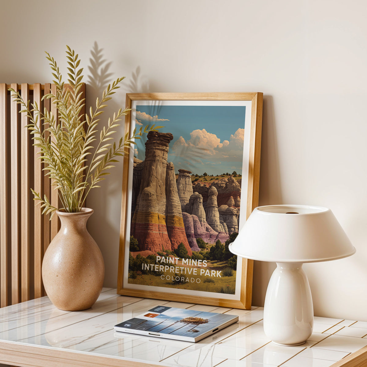 Paint Mines print framed in oak on a stone table with a white mushroom lamp and dried leaves