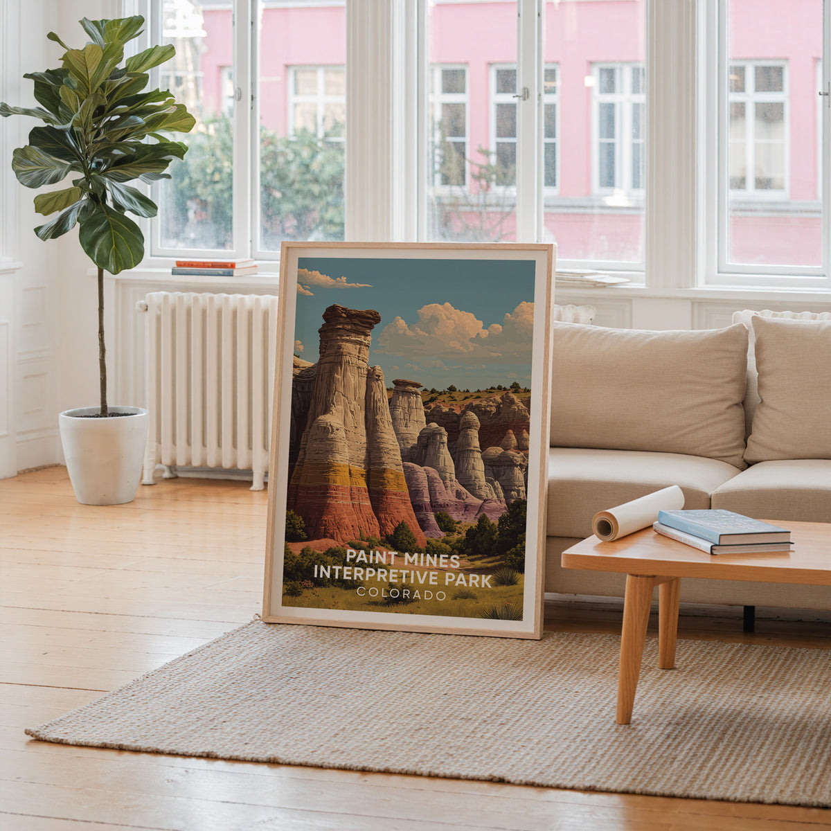 Paint Mines framed print leaning by a window facing a pink building above a cream sofa