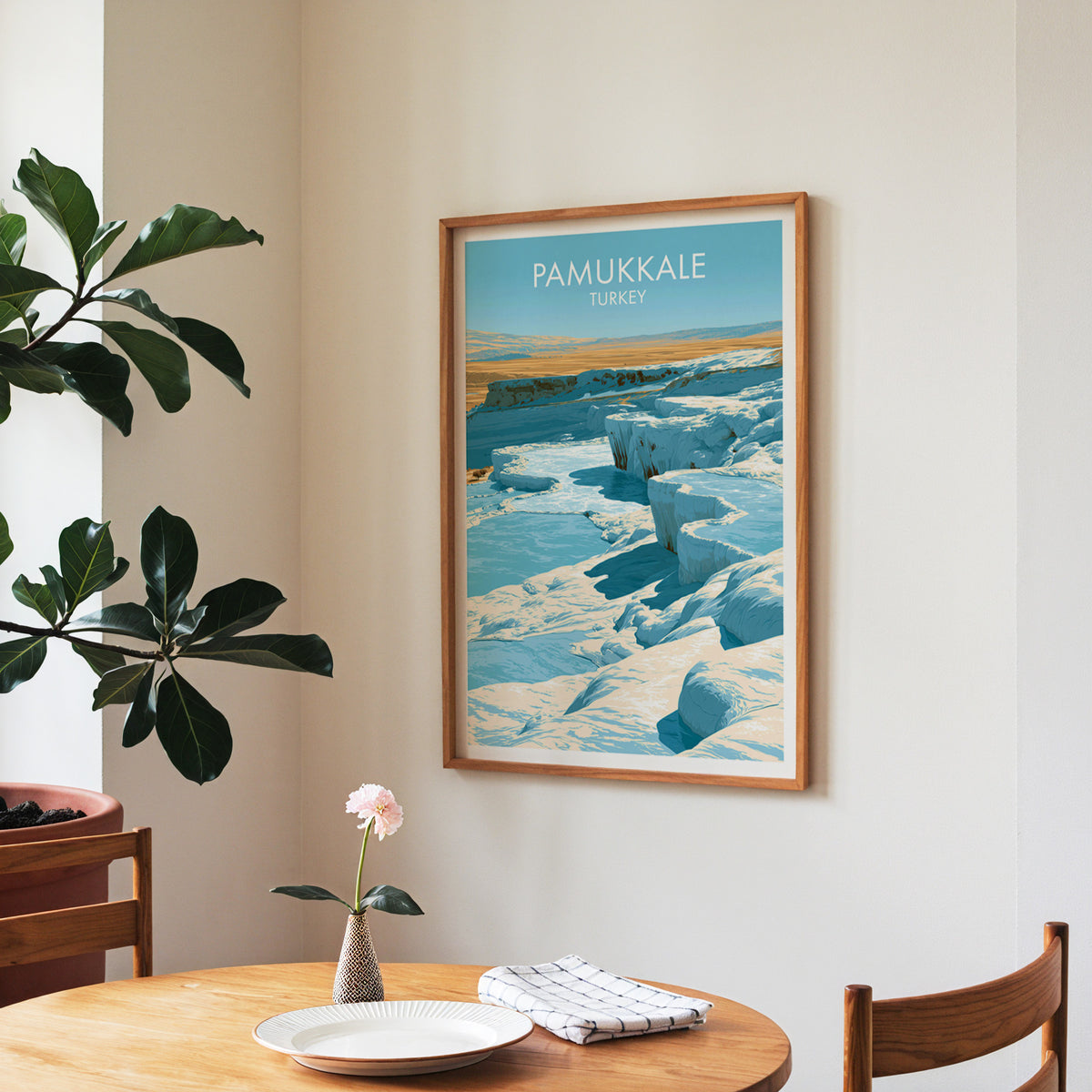 Pamukkale pools poster, walnut frame in a dining corner above a round table and a fiddle-leaf fig