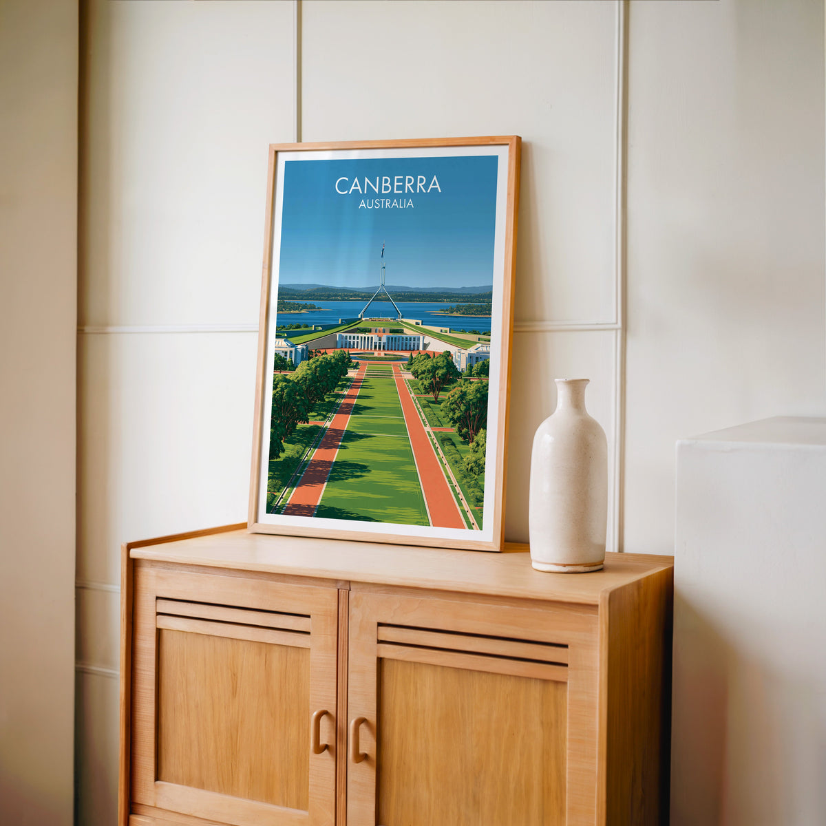 Symmetrical Canberra print in an oak frame on a light oak cabinet against a cream panelled wall