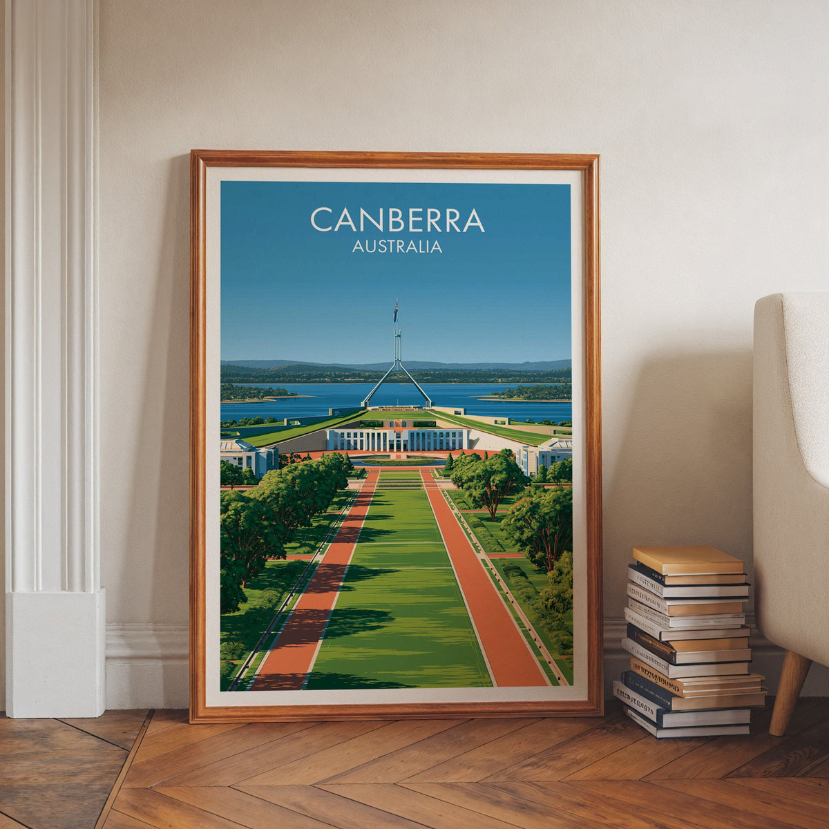 Capital city artwork in a walnut frame on herringbone floor beside book stacks and a pale armchair