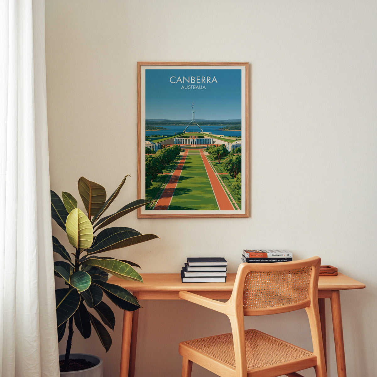 Lawn and lake poster in an oak frame above a wooden home office desk with a cane chair and books