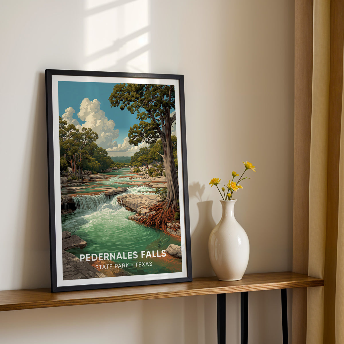 Texas Hill Country falls print in a black frame on a narrow console with yellow blooms