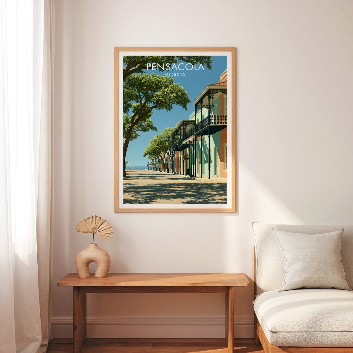 Live oak street poster in an oak frame on a white wall over a slim bench, cream armchair and palm fan