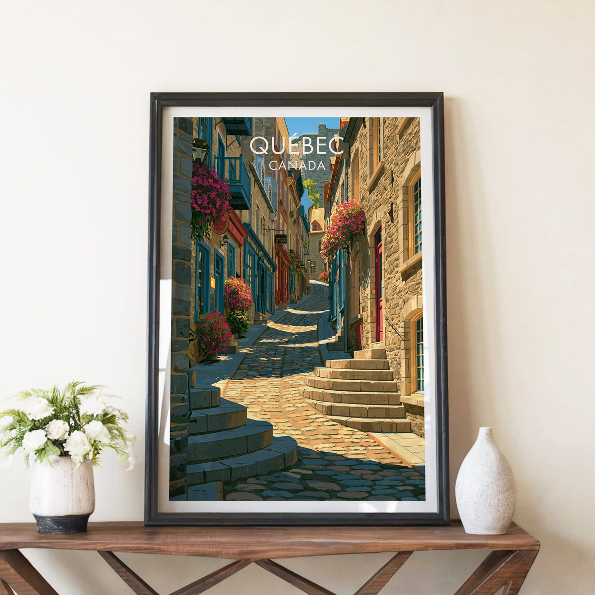 Old Quebec cobbled lane print in a black frame on a walnut console beside white peonies