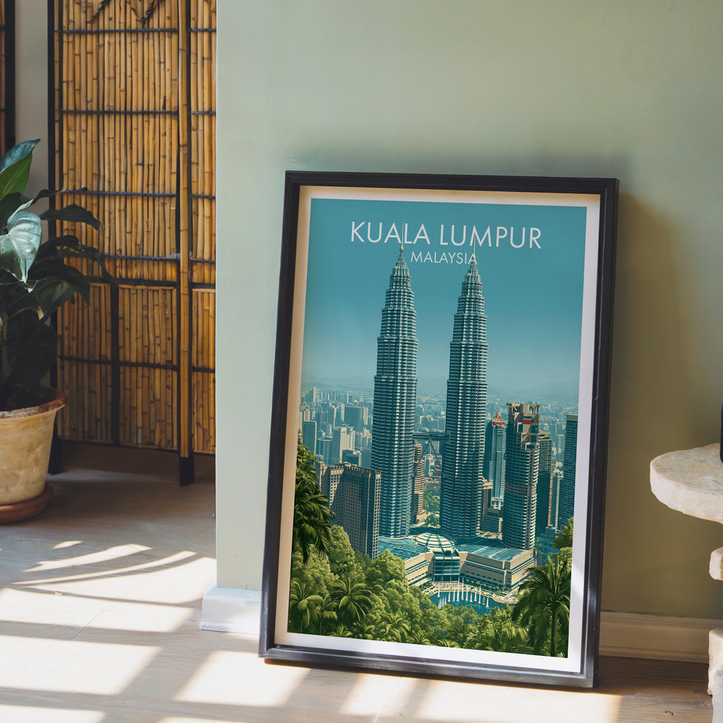 Petronas Towers Kuala Lumpur wall art in a black frame leaning against a sage green wall beside a bamboo screen