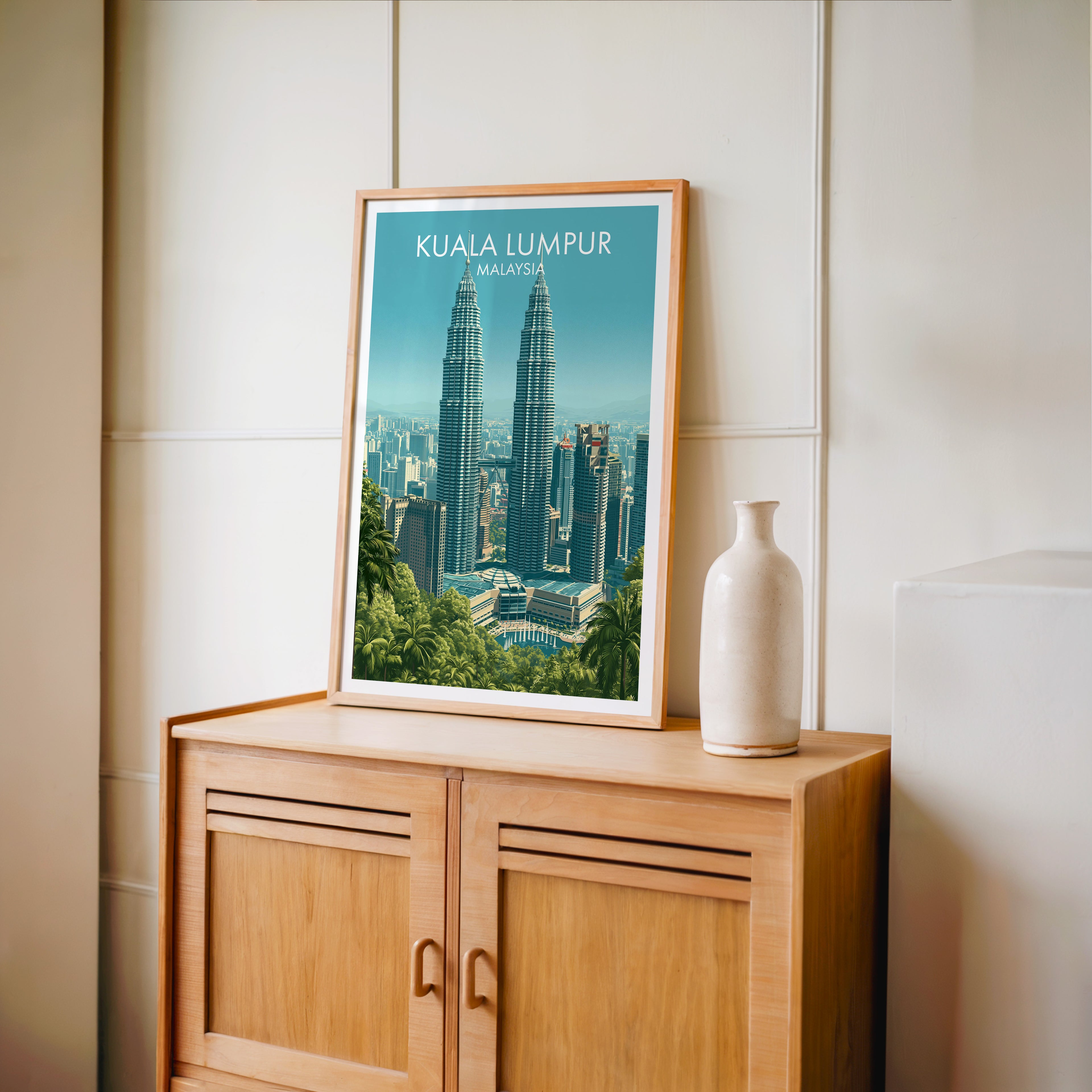 Small Petronas Towers Kuala Lumpur travel poster in an oak frame on a mid-century sideboard with a ceramic vase