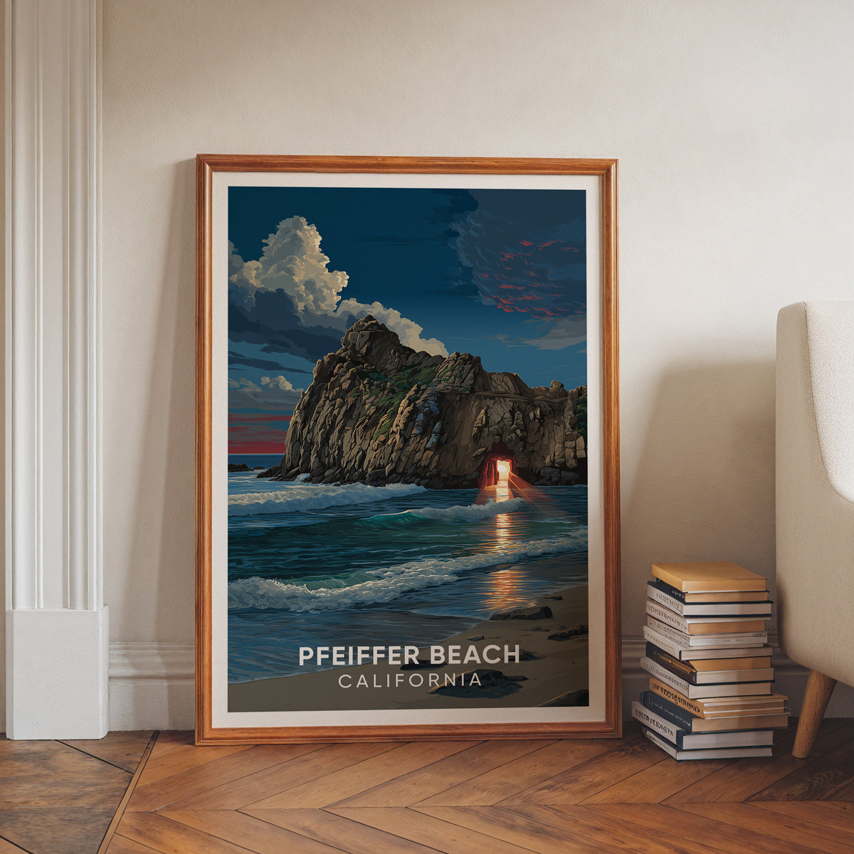 Big Sur sunset arch art in a walnut frame on a herringbone floor beside stacked books