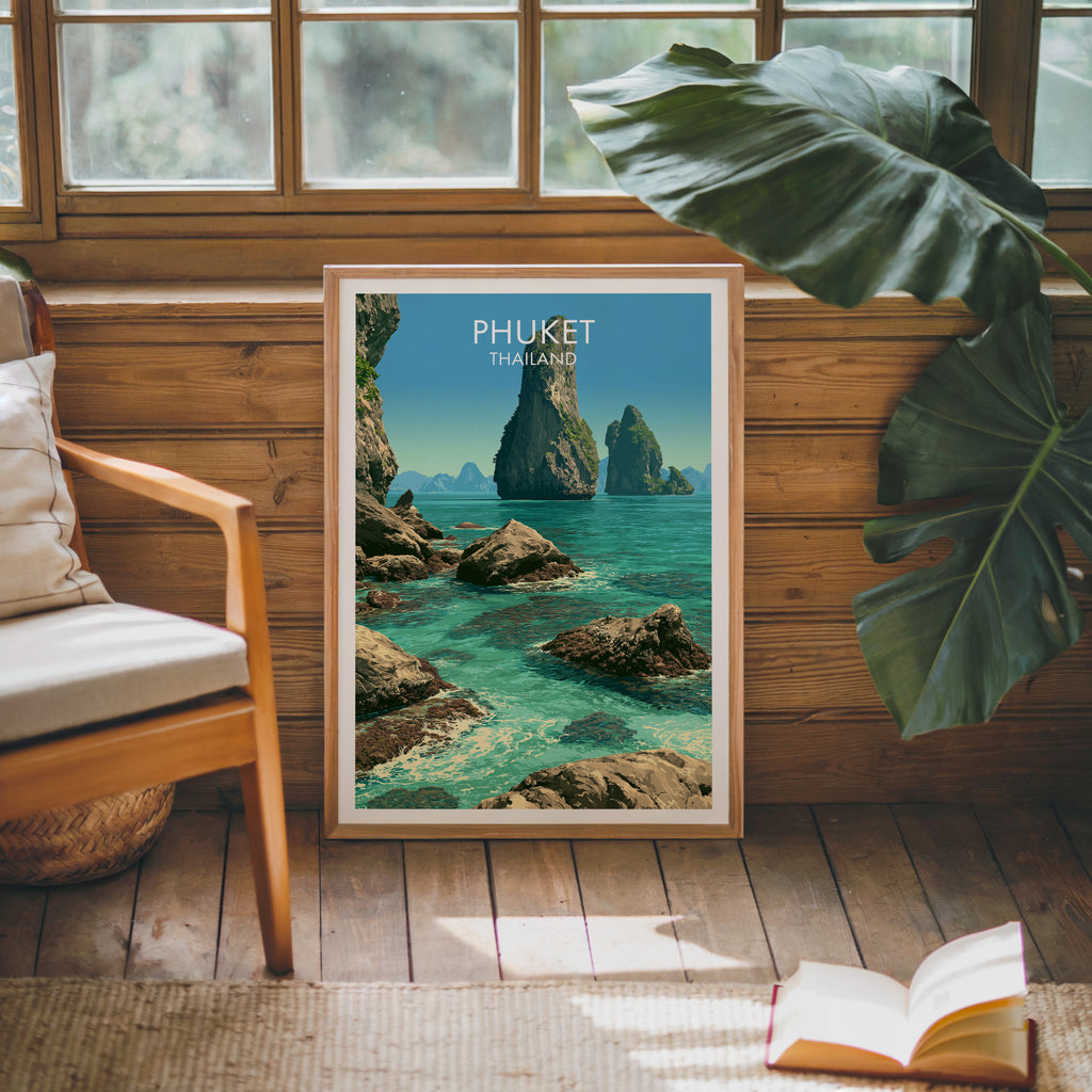 Framed Phang Nga Bay Phuket Thailand poster leaning against a timber cabin wall with monstera leaves and an open book