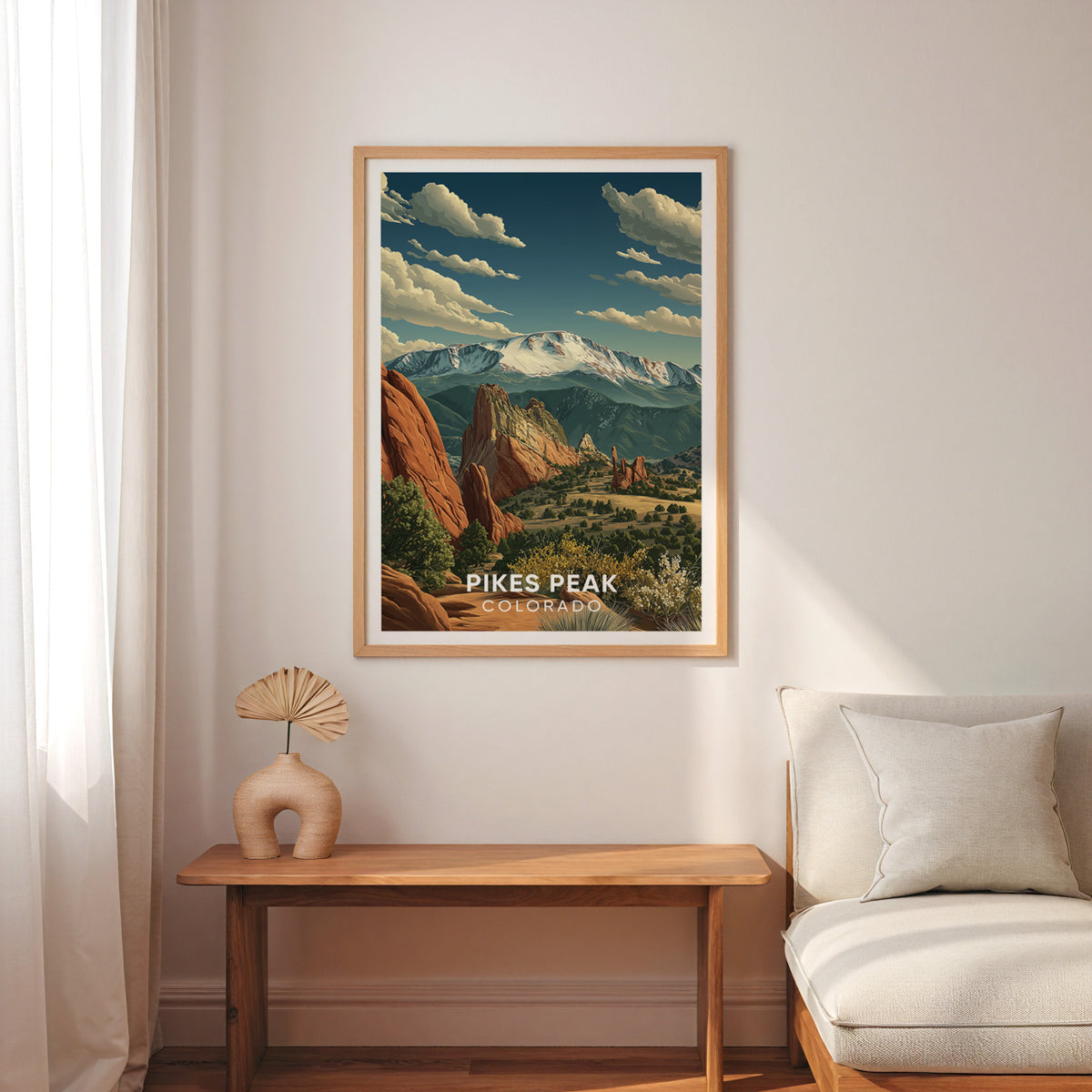 Pikes Peak travel print above a narrow wood bench with a cream armchair and sheer drapes