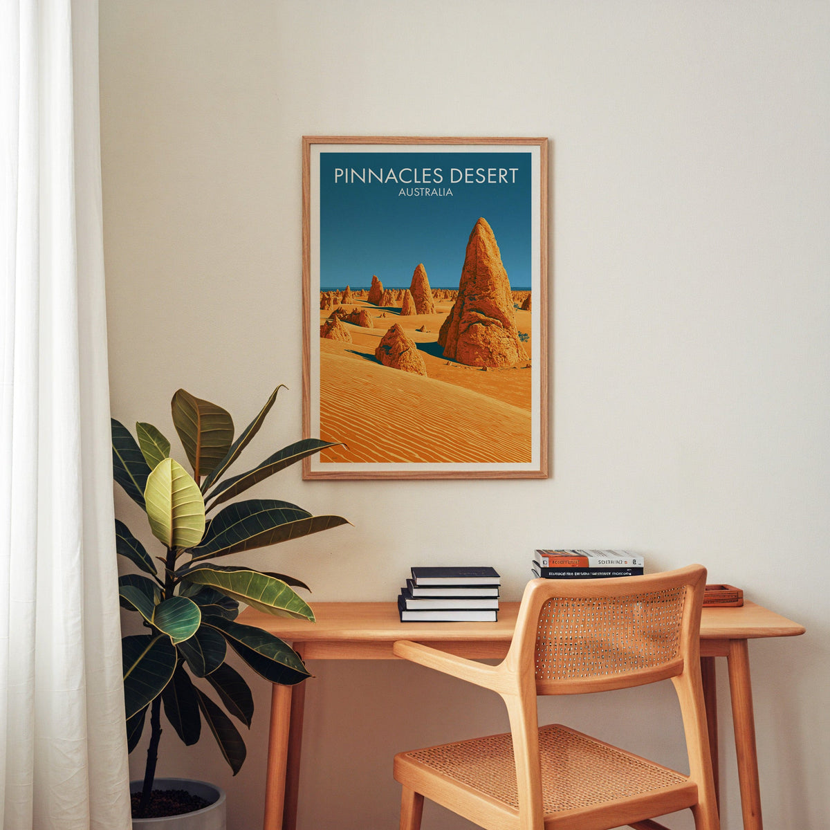 Australian desert artwork in an oak frame above a home office desk with a cane chair and rubber plant