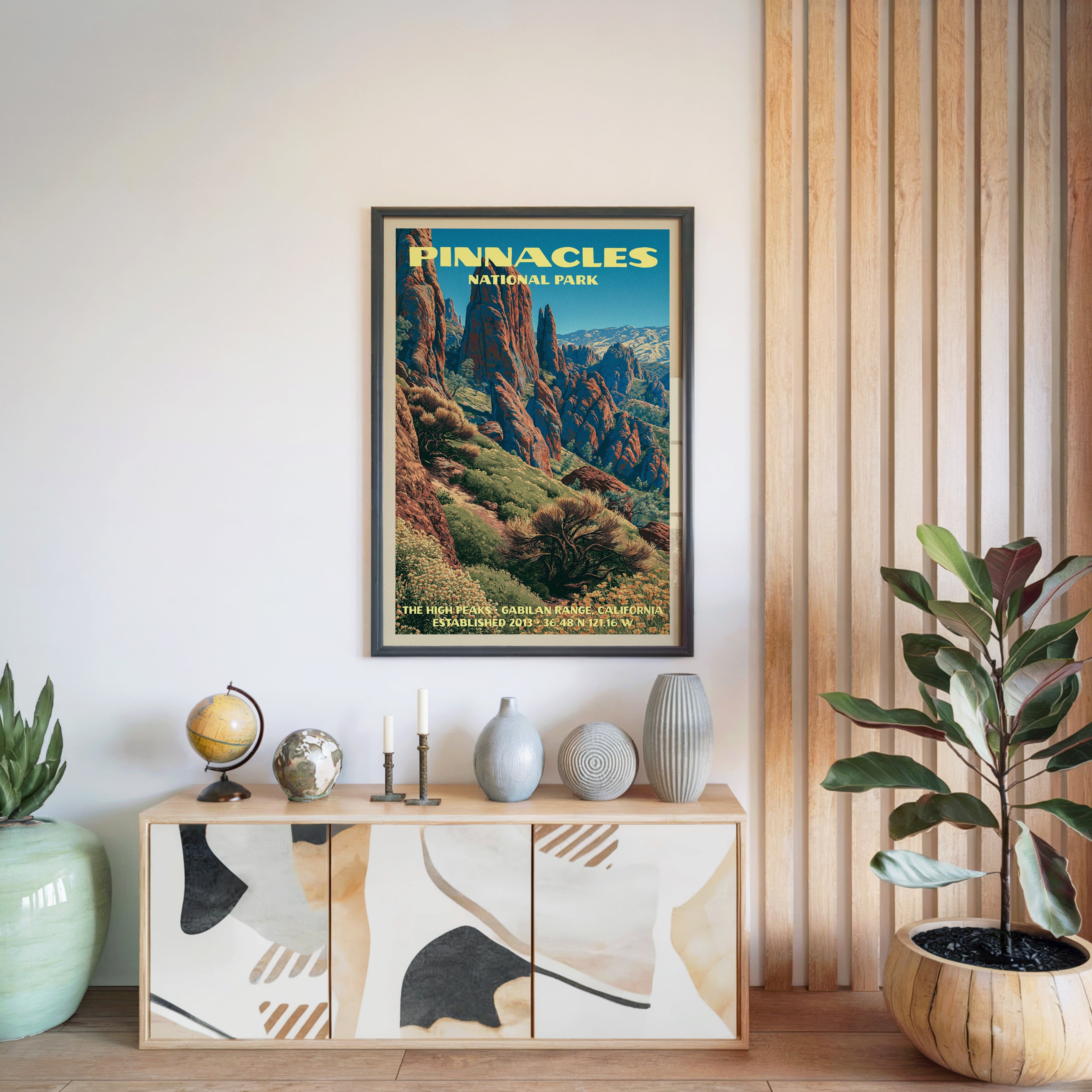 Pinnacles National Park poster in a black frame above a light wood sideboard by a slatted wall panel