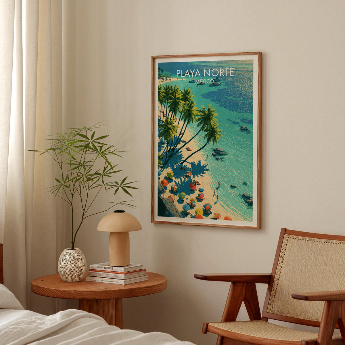 White sand and turquoise sea art in an oak frame above a bedside table with a mushroom lamp.
