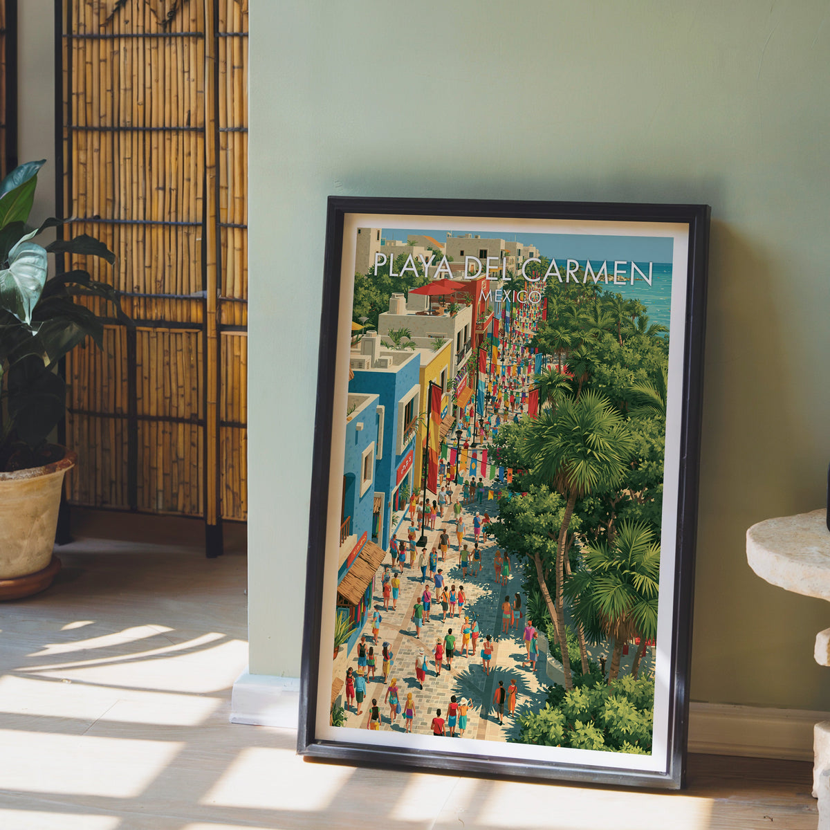 Palm-lined shopping street poster in a black frame leaning on a pale wood floor by a sage-green wall.