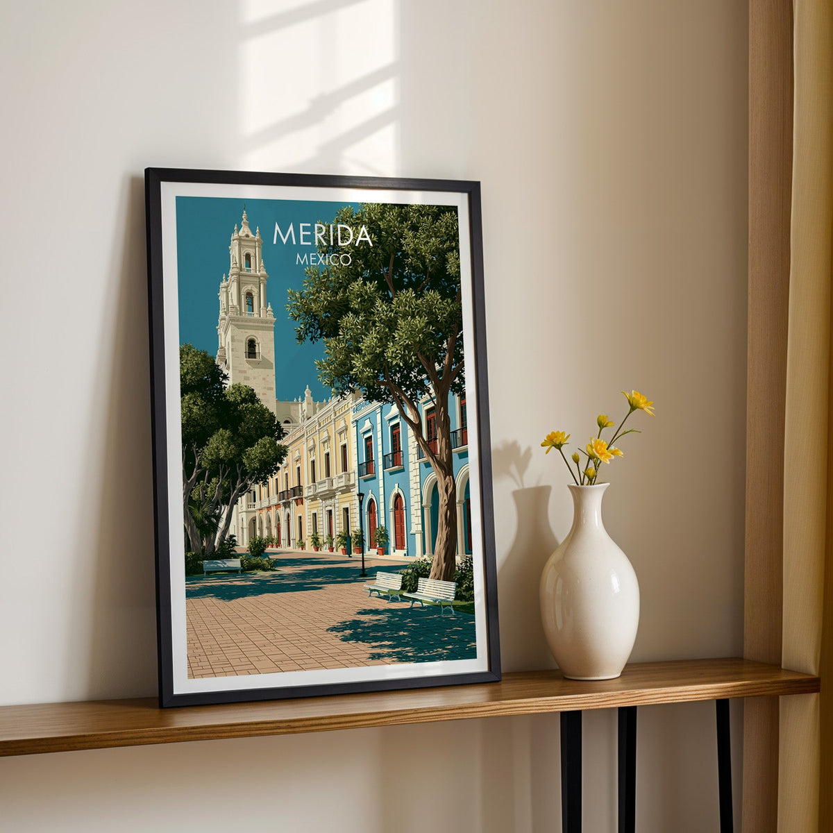 Buttermilk and sky-blue facades in a black frame on a wood shelf beside yellow daisies, cream wall.