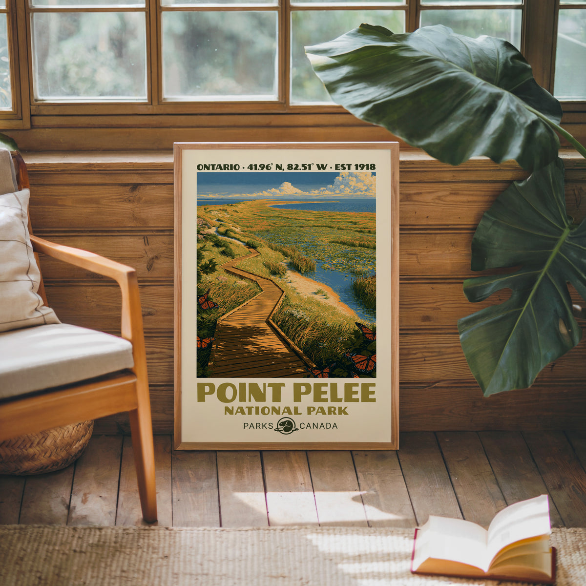 Point Pelee Canada vintage poster in an oak frame against a pine cabin wall beside a monstera