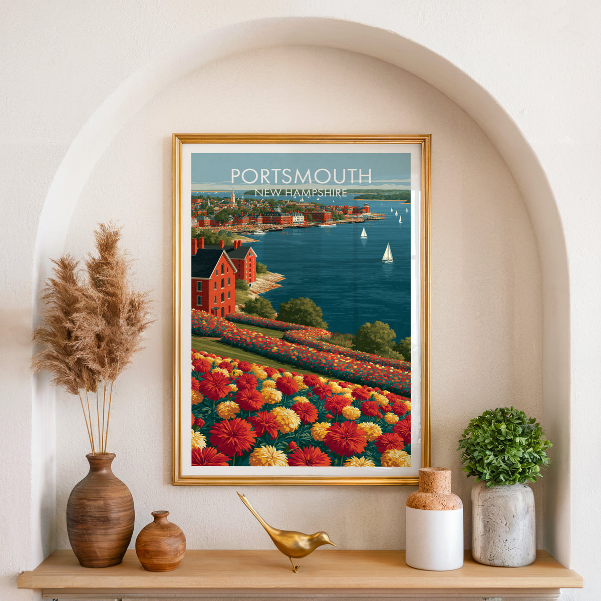 Piscataqua harbor print in a gold frame inside an arched wall niche with pampas grass and a brass bird.