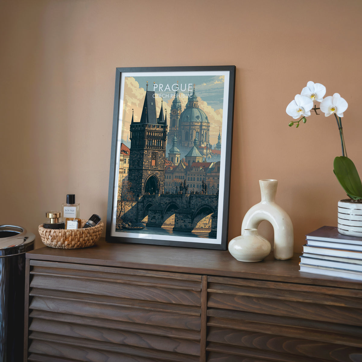 Prague travel wall art in a black frame on a walnut sideboard against a terracotta wall, beside an orchid