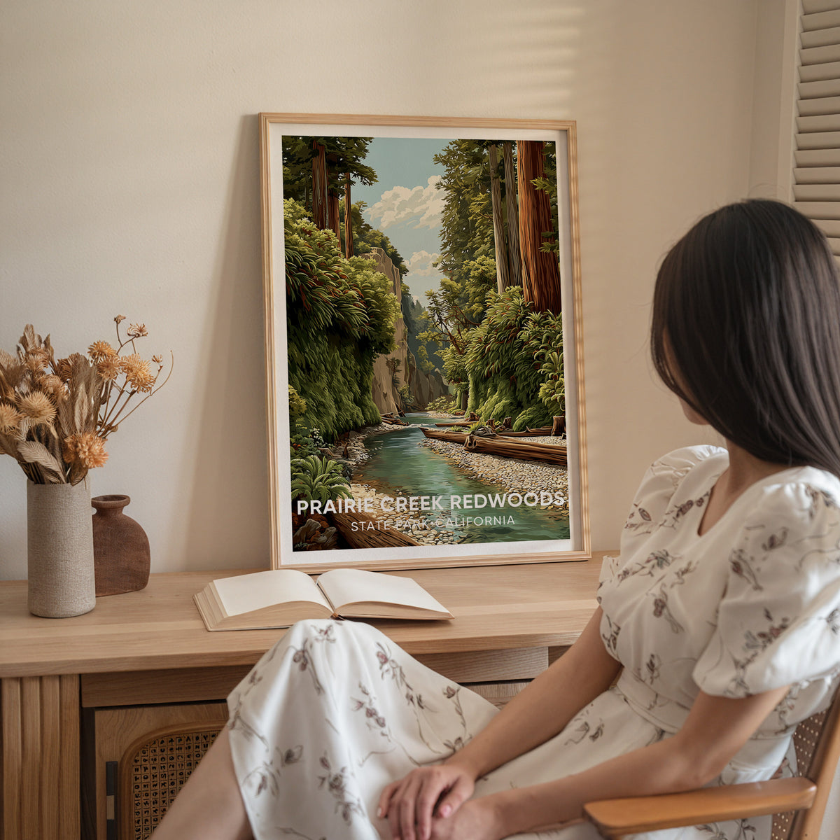 Woman in white seated beside the framed Prairie Creek Redwoods print on a sideboard