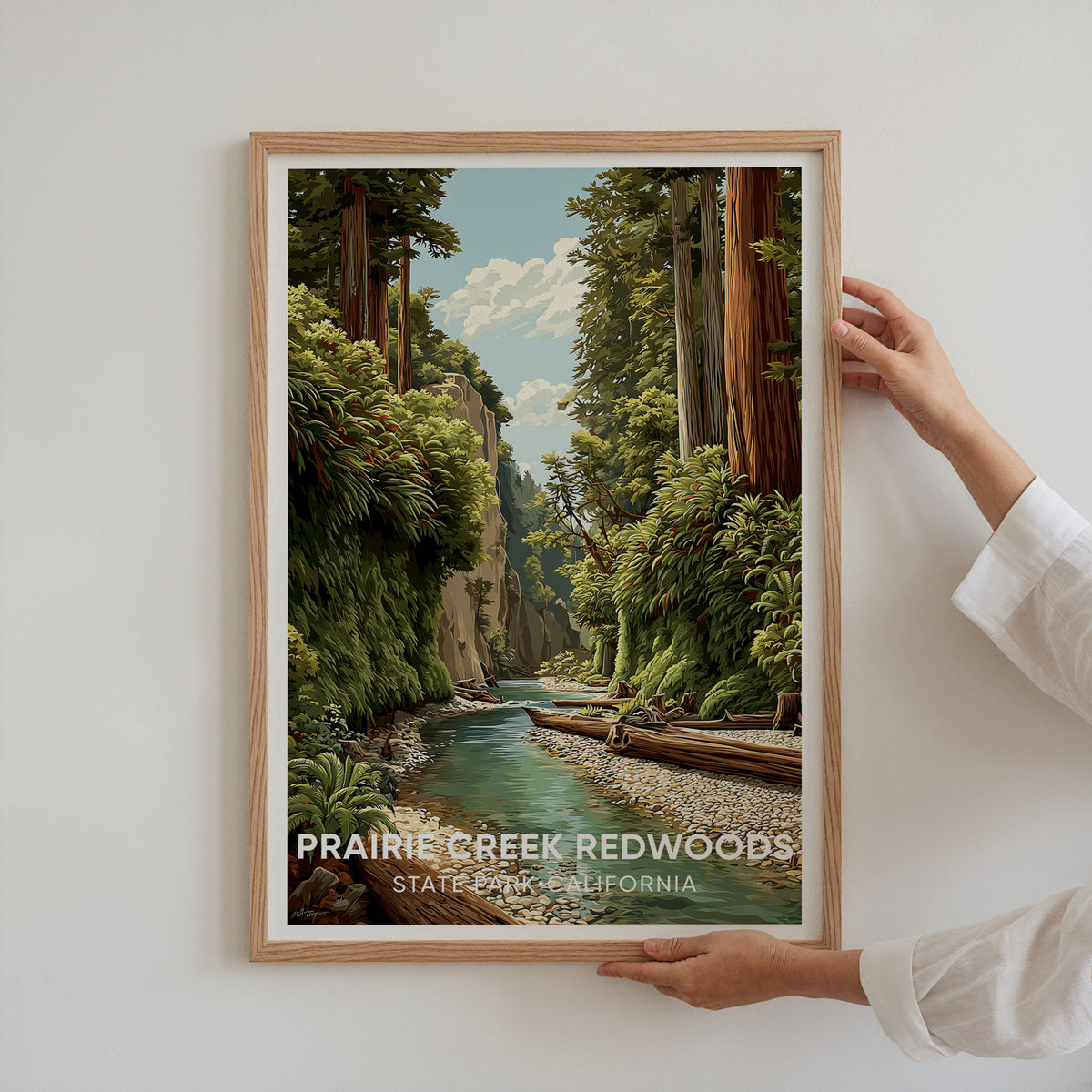 Two hands hold the framed Prairie Creek Redwoods poster against a white wall