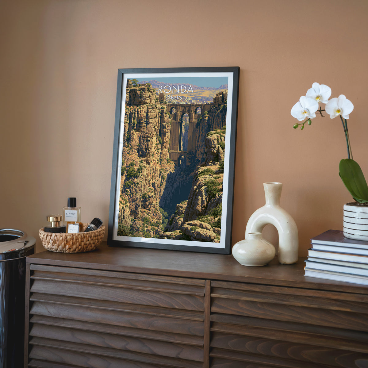 Andalusia gorge wall art, black frame on a walnut sideboard against a terracotta wall with an orchid