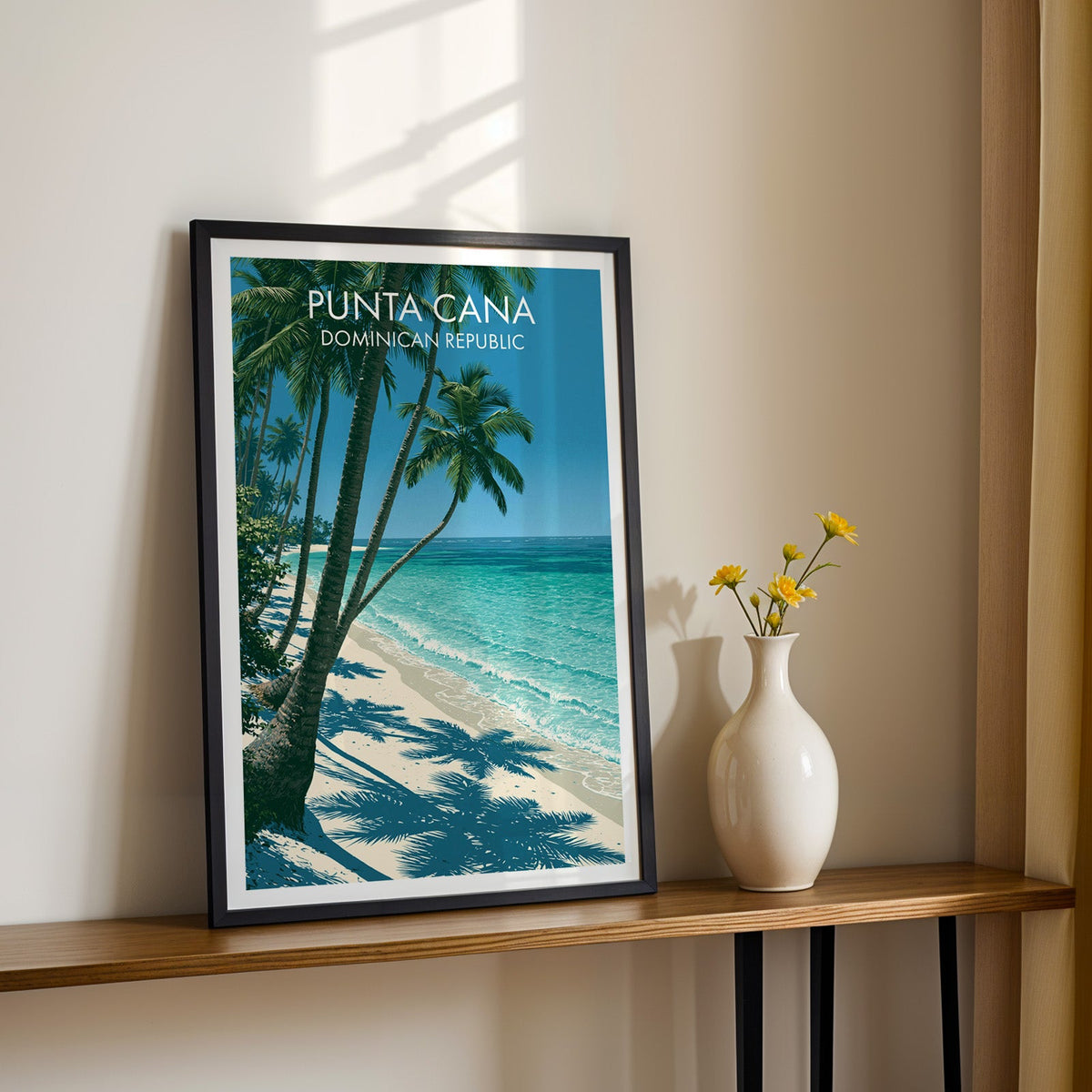 Dominican Republic beach poster, black frame on a slim wood shelf with yellow daisies on a cream wall