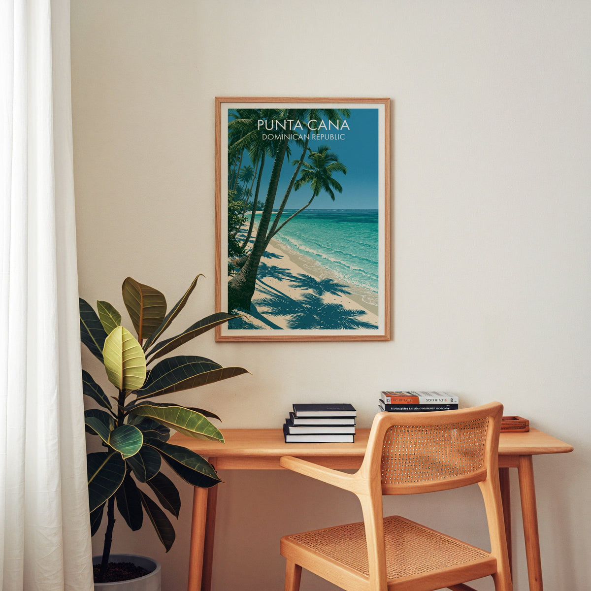 Tropical shoreline artwork in an oak frame above a wooden desk with a cane chair and a rubber plant