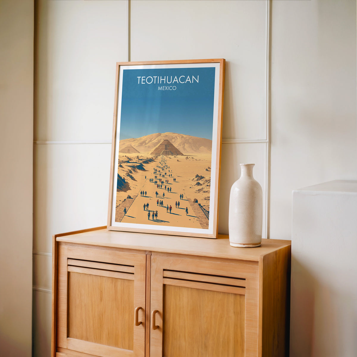 Ochre plain and blue sky print in an oak frame on a light oak cabinet by a cream panelled wall