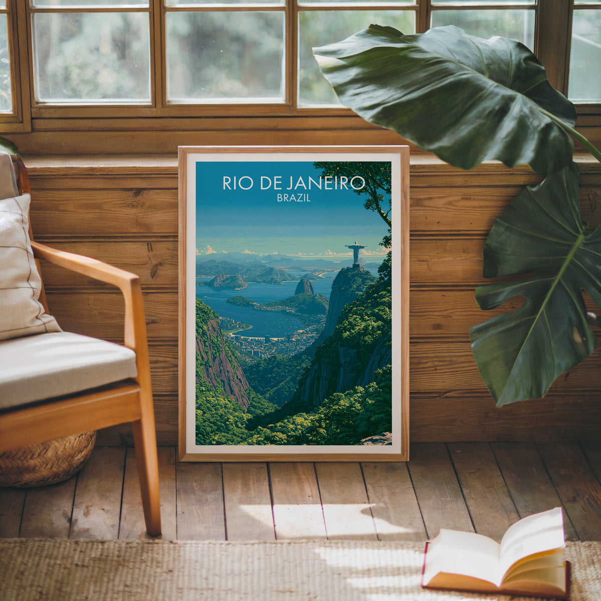 Guanabara Bay travel print in an oak frame against a pine cabin wall with a wood chair, monstera leaf and open book
