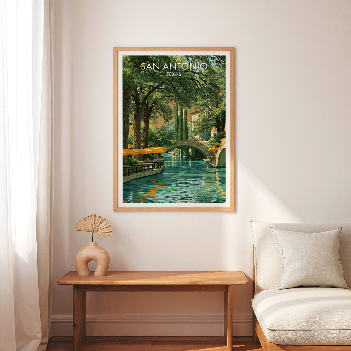 River Walk cafe umbrellas poster in an oak frame over a slim wood bench and cream armchair