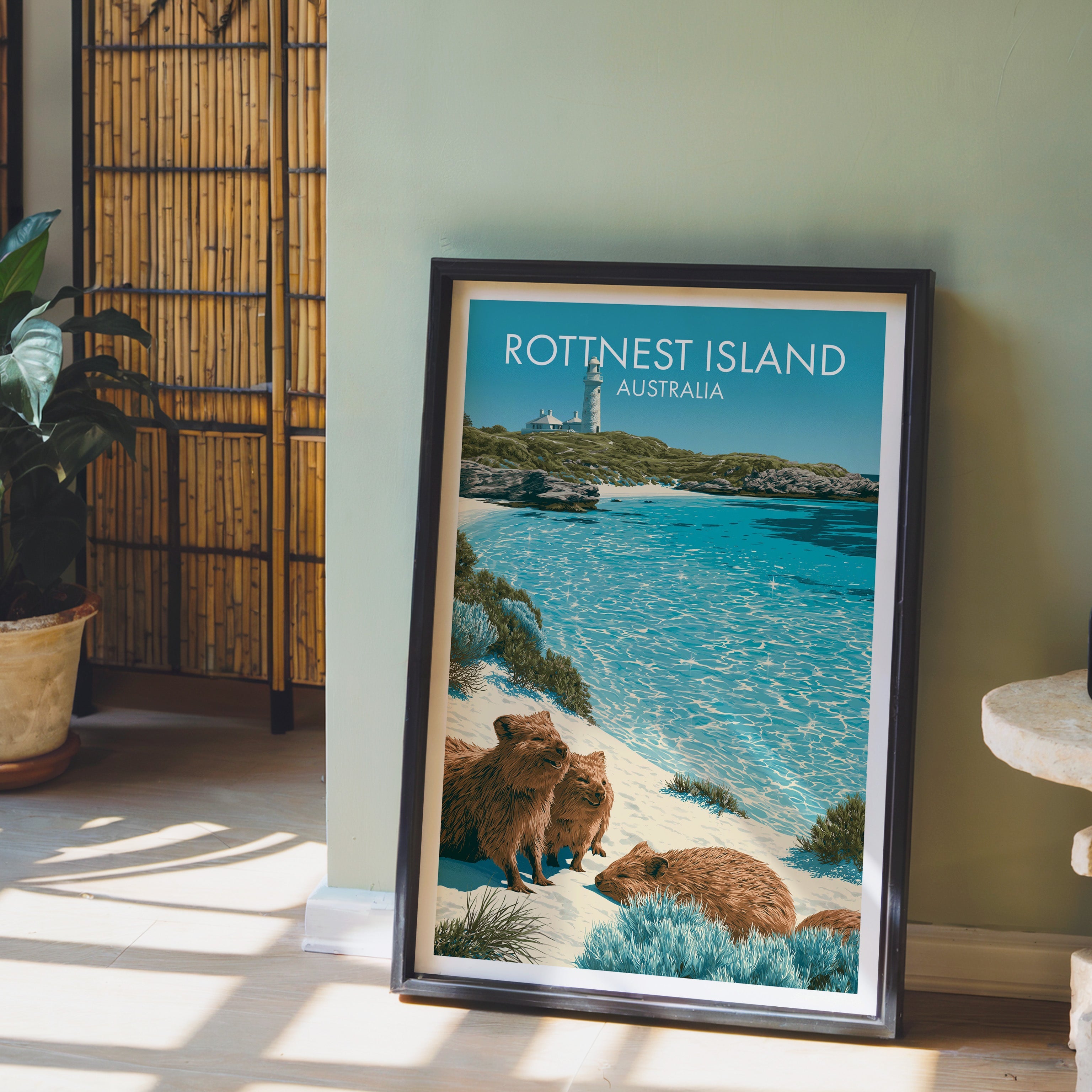 Lighthouse and quokka illustration in a black frame on pale wood floor by a sage wall and bamboo screen
