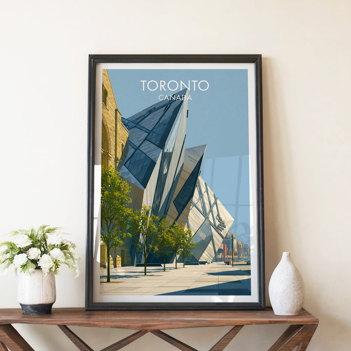 ROM Crystal Toronto print in a black frame on a walnut console beside white peonies