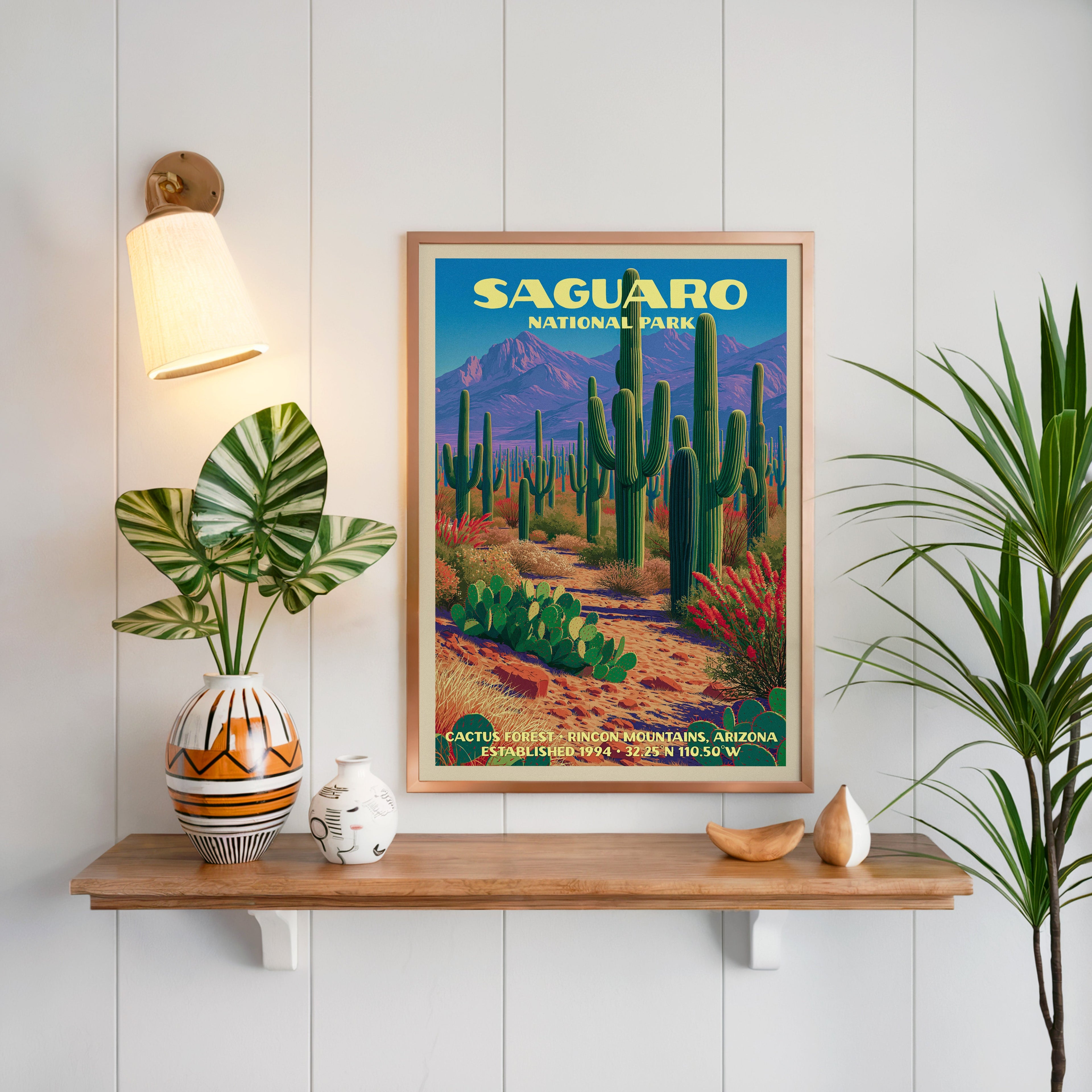 Cactus Forest Saguaro print framed on white panelling above an oak shelf with a patterned vase and sconce
