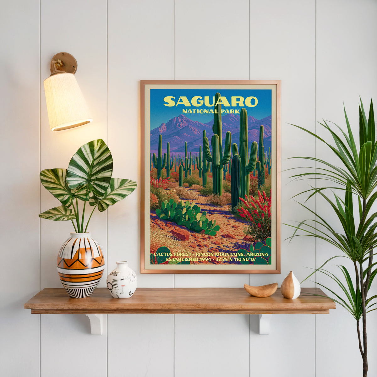 Cactus Forest Saguaro print framed on white panelling above an oak shelf with a patterned vase and sconce