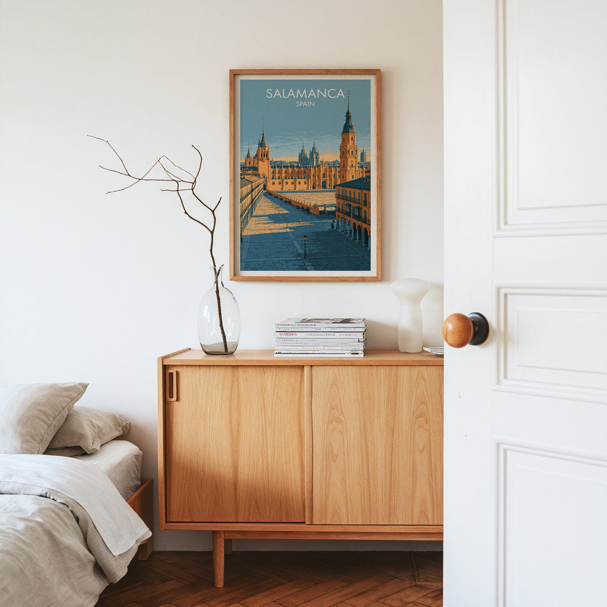 Salamanca sandstone plaza print, oak frame above a light oak sideboard with bare branches in a glass vase
