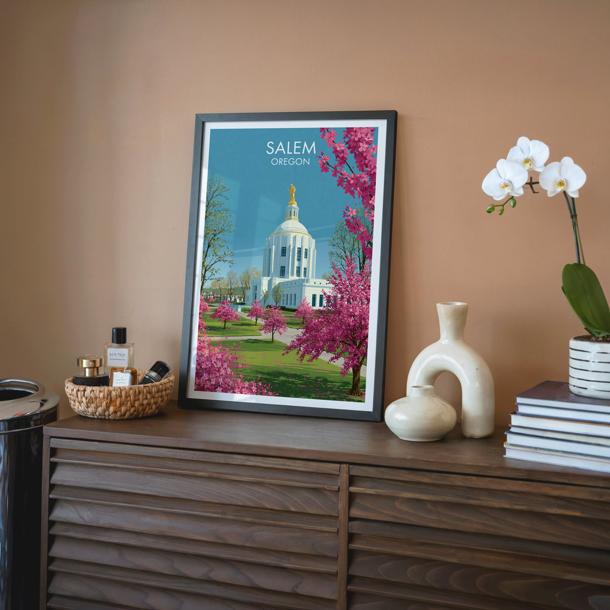 Oregon State Capitol print in a black frame on a walnut sideboard against a terracotta wall.