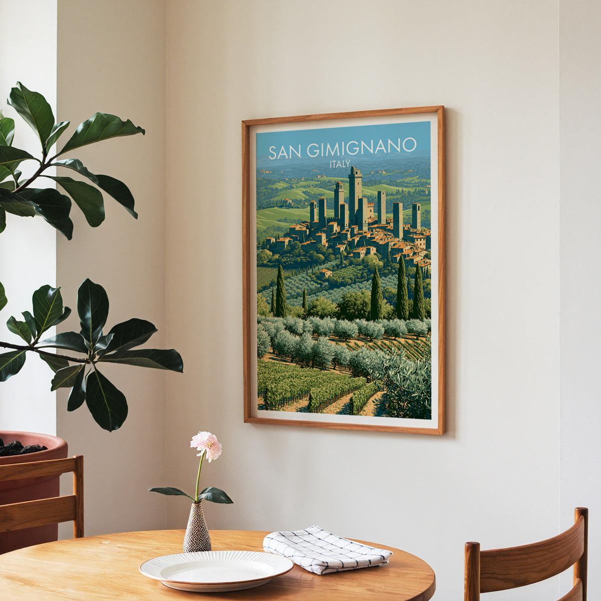 San Gimignano Tuscany poster, walnut frame in a dining corner above a round table and a fiddle-leaf fig