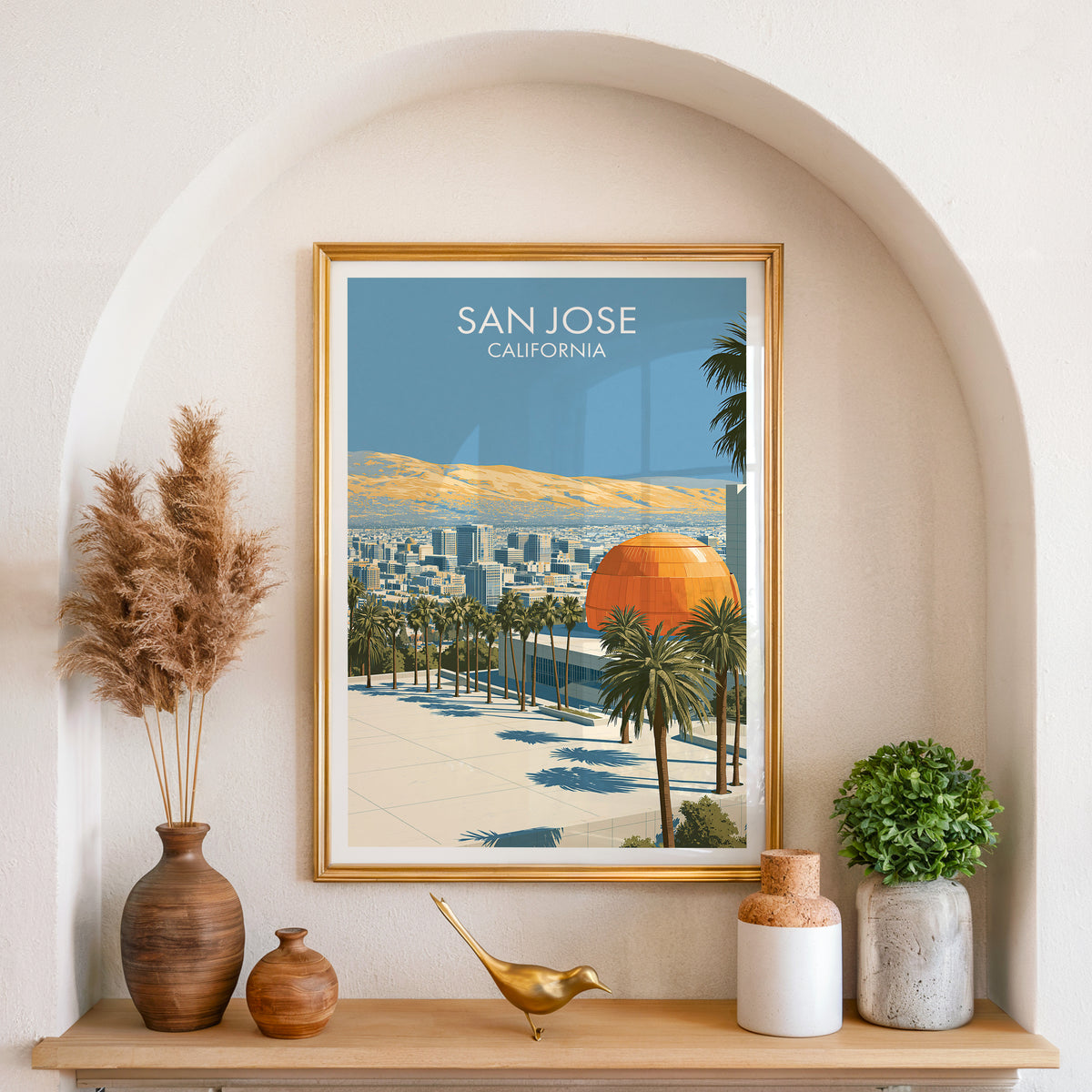 San Jose print in a gold frame inside an arched niche with pampas grass, a brass bird and small plants