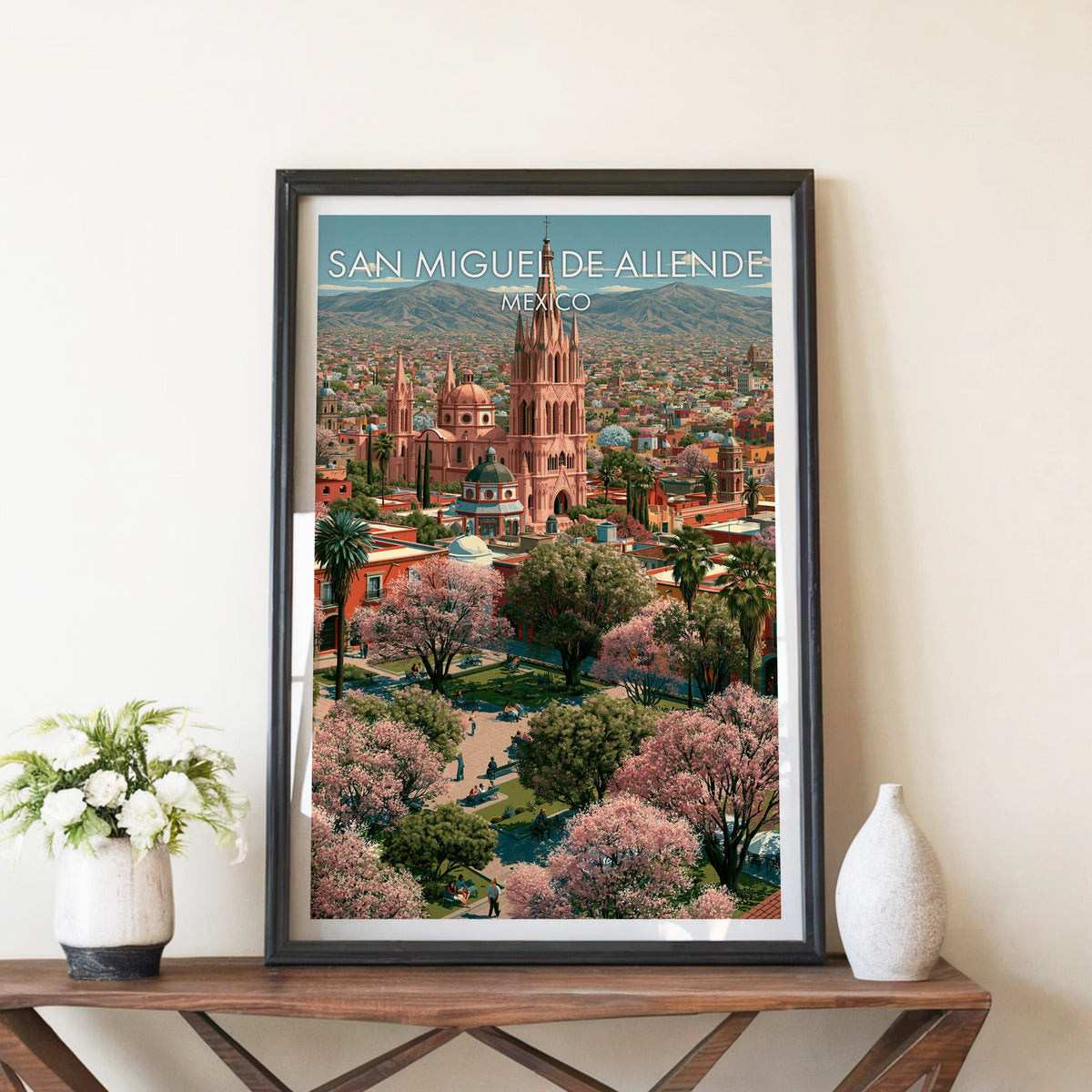 Rose-pink church tower artwork in a black frame on a walnut console with white peonies and a stone vase