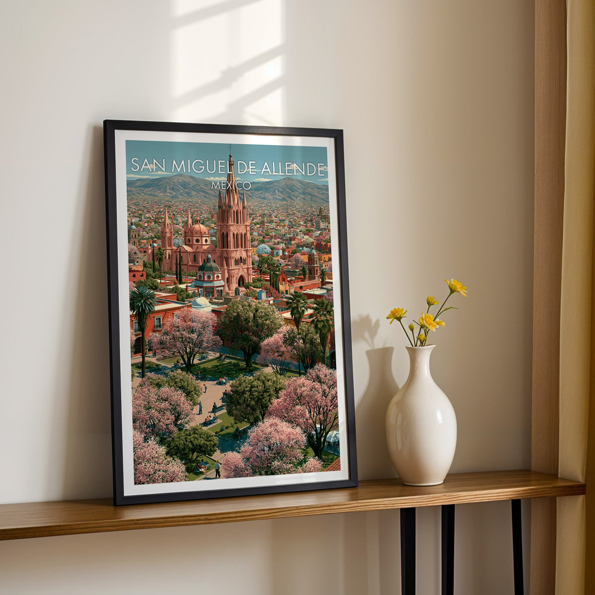 Blossom trees over a garden square, black frame on a wood shelf with yellow daisies on a cream wall
