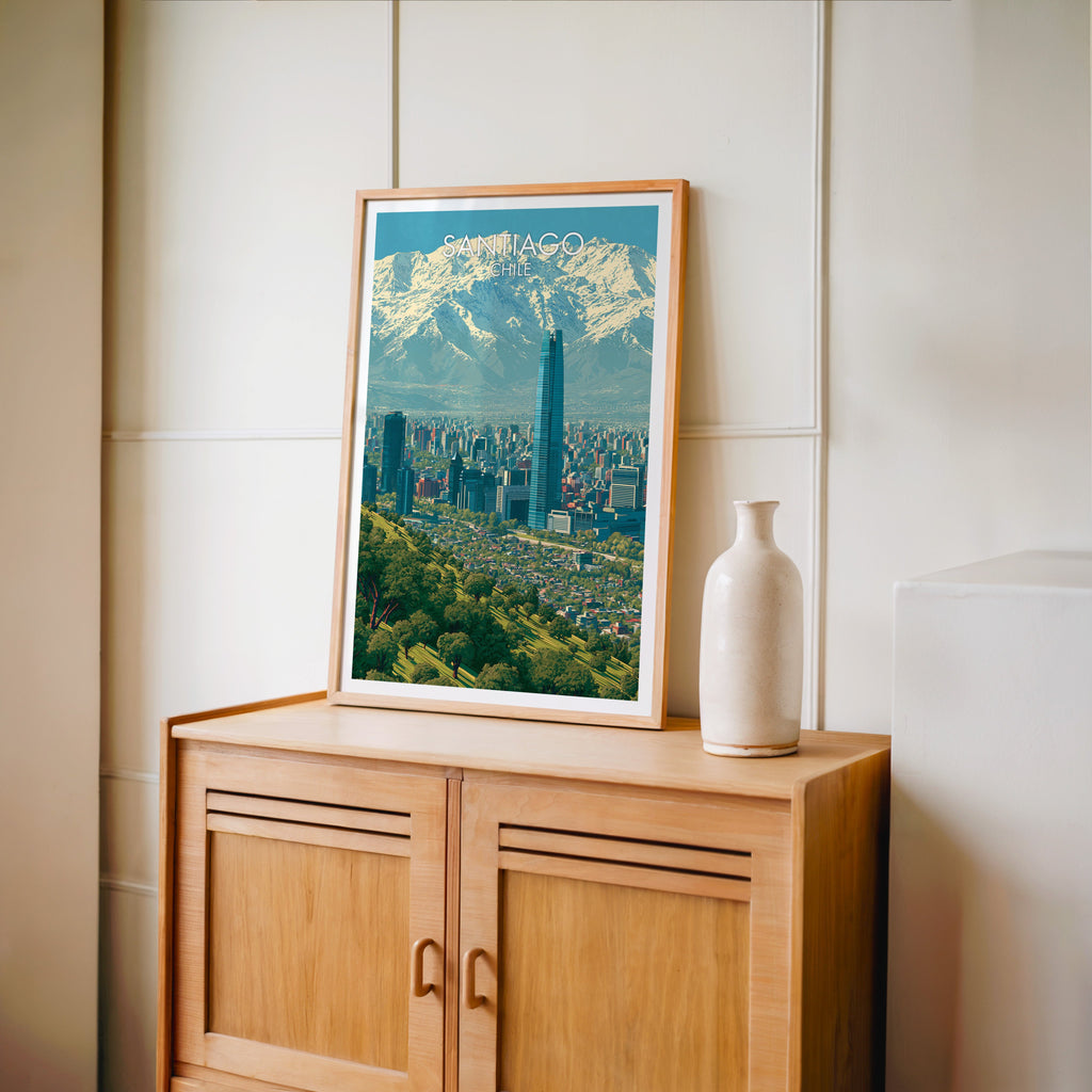 Santiago travel print in an oak frame standing on a pale oak cabinet against a cream panelled wall with a tall vase