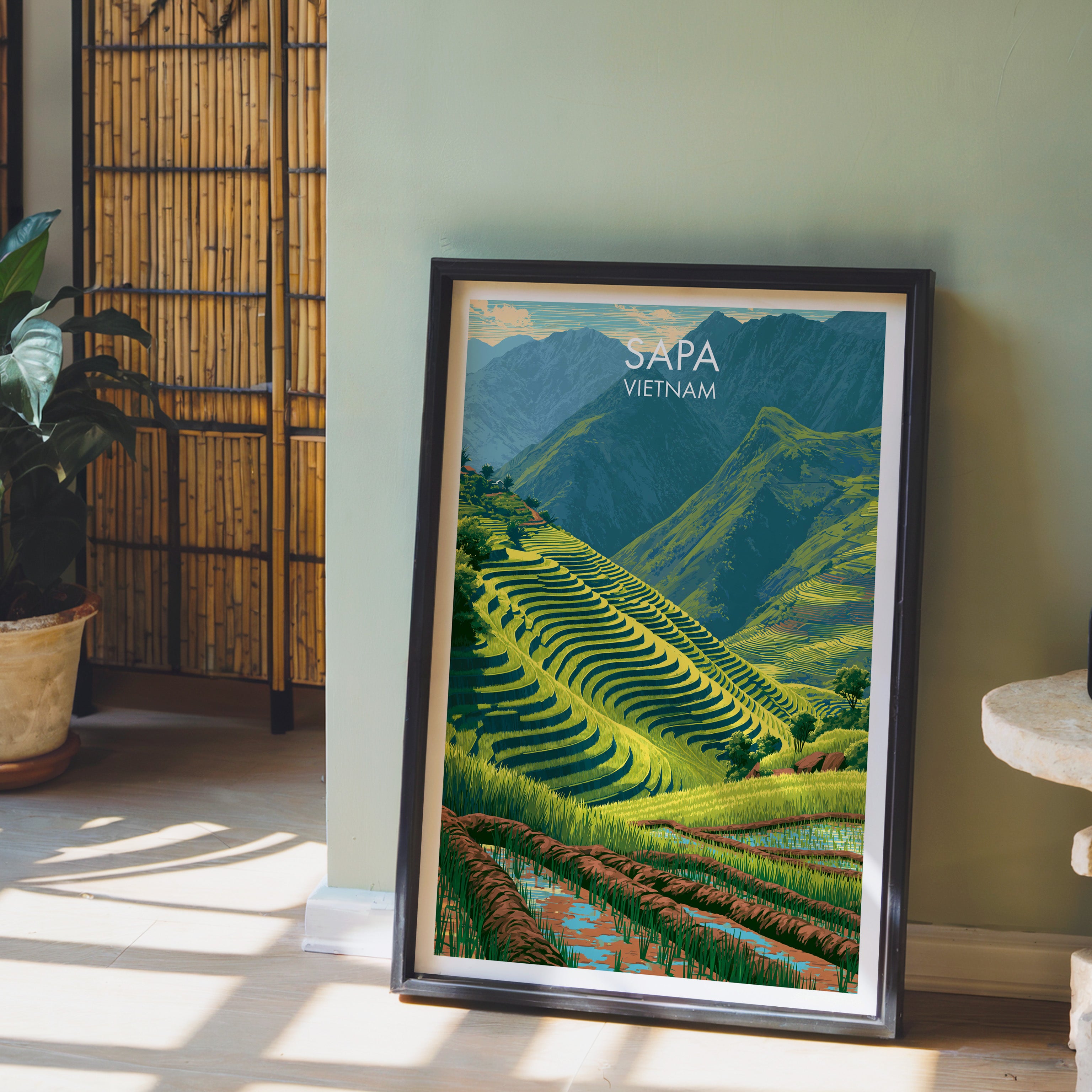 Sapa Vietnam wall art in a black frame leaning against a sage green wall beside a bamboo screen