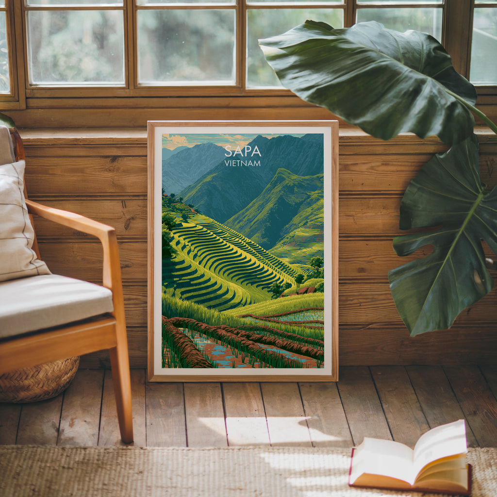 Framed Sapa Vietnam poster leaning against a timber cabin wall with monstera leaves and an open book