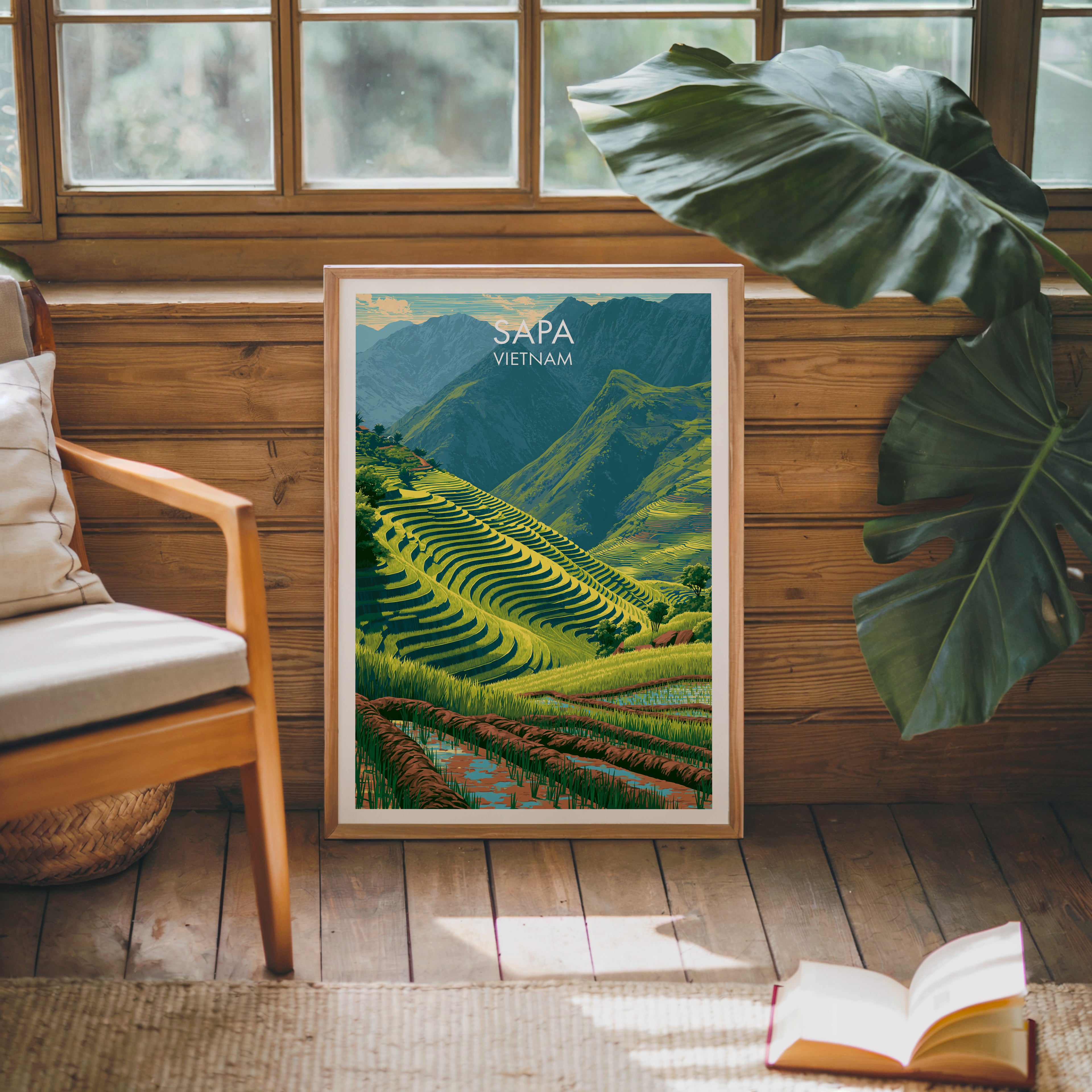 Framed Sapa Vietnam poster leaning against a timber cabin wall with monstera leaves and an open book