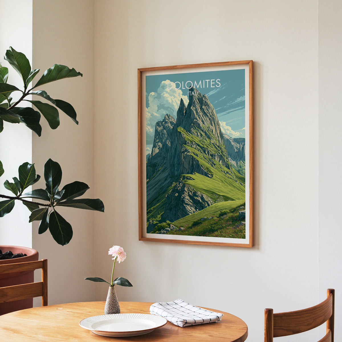 Dolomites travel wall art in a walnut frame over a round dining table with a plate and a rose