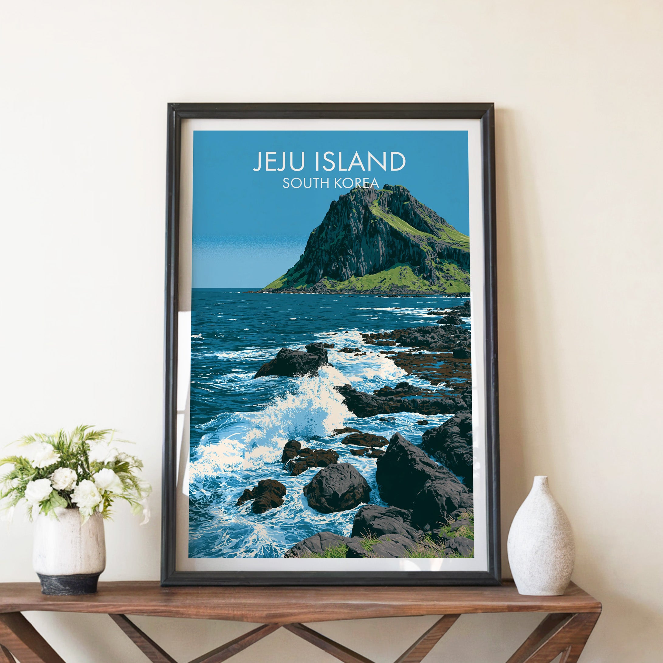Seongsan Ilchulbong Jeju Korea travel poster in a black frame on a wooden console table with white flowers