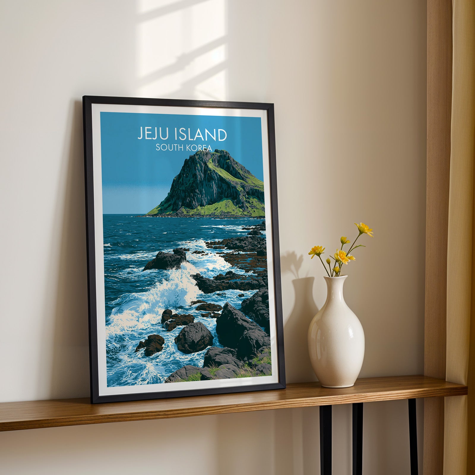 Black framed Seongsan Ilchulbong Jeju Korea print on a narrow hallway console in sunlight, styled with yellow flowers