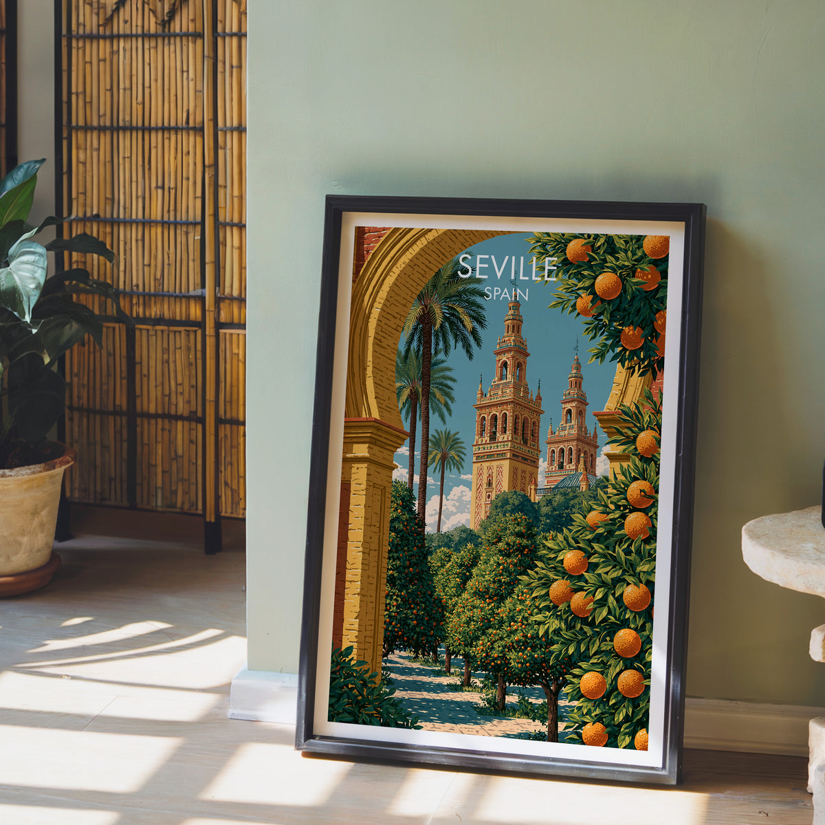 Seville Giralda poster leaning on a sage green wall beside a bamboo screen and a potted plant